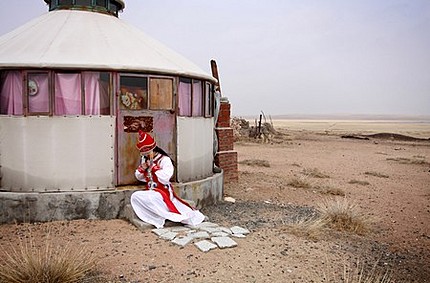 A tourist tries on a traditional Inner Mongolian dress next to a yurt on the degraded grasslands of the region. 1